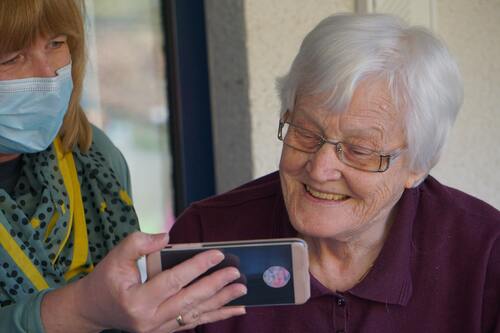elderly lady has smartphone explained to her